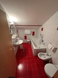 圣坎迪朵Hotel Brandl的红白色的浴室设有两个盥洗盆和一个浴缸。