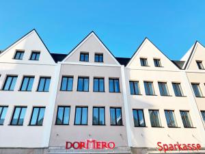 黑尔斯布鲁克DORMERO Hotel Hersbruck的前面有红色标志的白色建筑