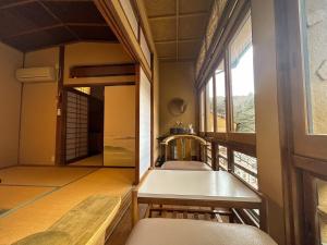 AtoichiArifuku Onsen Yoshidaya的客房设有桌椅和窗户。