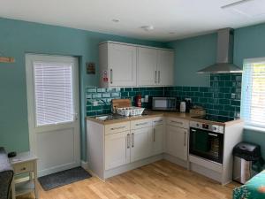 马丁Walnut Lodge, Timberland的厨房配有白色橱柜,墙壁上铺有绿色瓷砖。