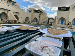 Qaryat at Ta‘mīr as SiyāḩīyahLake House by Tunisia Green Resort的桌边桌边的两盘食物
