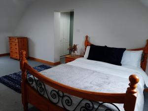 米尔敦马尔贝Skye's Atlantic Retreat的一间卧室配有一张带白色床单的木床