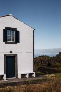 Canto da AreiaLiiiving in Açores - Ocean View House的白色的建筑,设有绿门和窗户