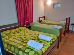拉班达La Casita的一间设有三张床的客房,配有绿色和黄色的床单