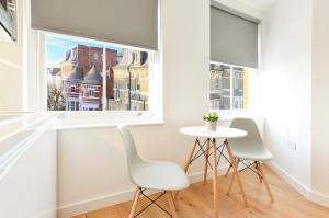 伦敦West Hampstead Serviced Apartments by Concept Apartments的一间带桌子和两把椅子的用餐室以及窗户。