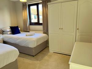 BawburghBeautiful & Private 3 bed detached house with driveway Parking的一间卧室设有两张床、一个橱柜和一个窗口。