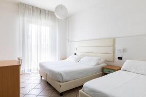里米尼帕洛斯酒店的酒店客房设有两张床和窗户。
