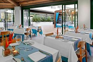 英格兰海滩Hotel Gran Canaria Princess - Adults Only的餐厅设有白色的桌椅和窗户。
