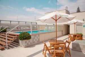 塔克纳Dorado Hotel Boutique - Tacna的一个带游泳池、桌子和遮阳伞的庭院