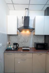 古尔冈The Lodgers 1 BHK Serviced Apartment Golf Course Road Gurgaon的厨房配有白色橱柜和炉灶烤箱。
