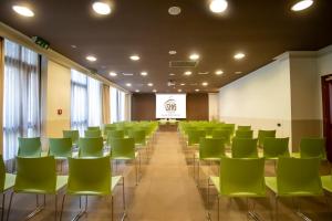 维琴察SHG德拉维尔酒店的一间会议室,配有绿色椅子和屏幕