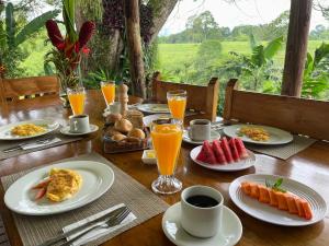 金巴亚MuchoSur Quimbaya的一张木桌,上面放有早餐食品和橙汁盘
