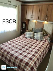 桑当First Steps Caravan Rentals的一间卧室配有一张带铺着平底毯的床