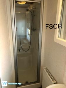 桑当First Steps Caravan Rentals的一间带卫生间的浴室内的玻璃淋浴间