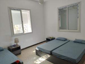 GabèsDar chenini的一间卧室设有两张床和两个窗户。