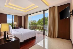 努沙杜瓦努沙杜瓦巴厘酒店的一间卧室设有一张床,阳台配有电视。