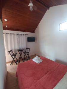 圣佩德罗塞拉Suites Estrela的一间卧室配有红色的床和桌椅