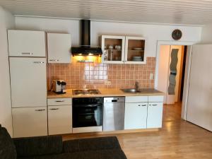 萨尔巴赫Landhaus Klausner的厨房配有白色橱柜和炉灶烤箱。
