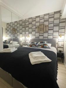 多维尔Sublime Coeur Deauville的一间卧室配有一张带毛巾的大型黑色床