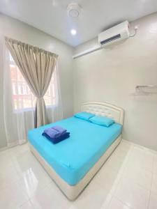 PendangHZ HOMESTAY PENDANG的窗户客房内的一张蓝色的床