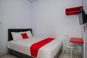 美娜多RedDoorz at Lapangan Bandara Sam Ratulangi Manado的一间卧室配有一张床铺,床上铺有红色毯子
