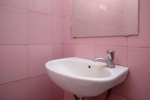 美娜多RedDoorz at Lapangan Bandara Sam Ratulangi Manado的粉红色瓷砖浴室内的盥洗盆和镜子