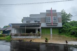 美娜多RedDoorz at Lapangan Bandara Sam Ratulangi Manado的雨中的房子,一条洪水泛滥的街道