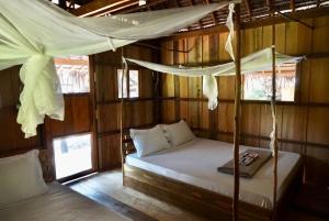 瓜隆岛Lily's Riverhouse的小木屋内一间卧室,配有一张床