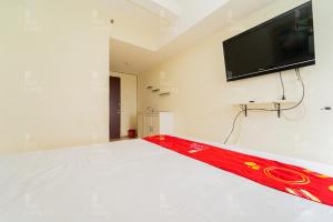 万隆RedLiving Apartemen Tamansari Panoramic - Santuy Agency Lobby P1 9的客房设有一张壁挂式平面电视的床。