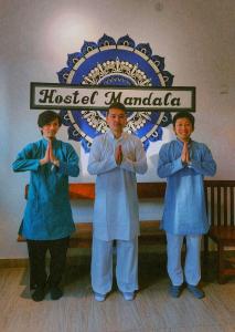 安君纳Hostel Mandala的三个穿着蓝色长袍的人在标志前祈祷