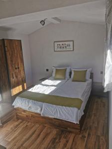 多布里尼什特Ергини的一间卧室配有一张带白色床单和绿色枕头的大床。