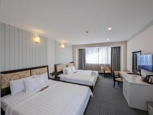 胡志明市Đông Kinh Hotel的酒店客房设有两张床和电视。