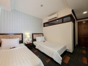 胡志明市Đông Kinh Hotel的酒店客房设有两张床和窗户。