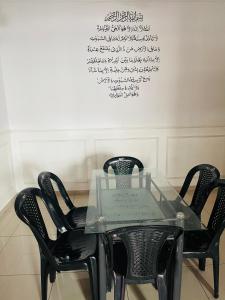 卢穆特NO 121 NAZIRIN HOMESTAY TMN DESA MANJUNG的一张玻璃桌,里面摆放着四把黑色椅子