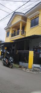 茂物FAI Bogor Backpacker by SPAZIE的停在黄色房子前面的摩托车