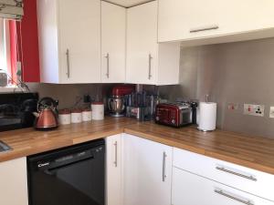 特鲁罗The Cottage Cox Hill Chacewater的厨房配有白色橱柜和黑色洗碗机