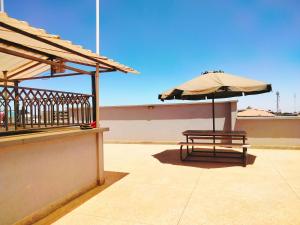 KikuyuPine Residency w Secure Parking, Wifi, Netflix & Rooftop Views的阳台的遮阳伞和长凳