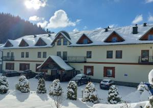 克雷尼察Piastun SPA&Wellness Krynica-Zdrój的一座白色的大建筑,屋顶上积雪