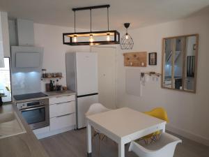 塞普特梅斯·莱瓦隆T2 tout neuf avec Parking à 10km d'Aix et Marseille的厨房配有白色桌子和白色冰箱。