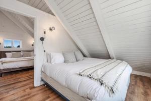 洋滨市Tidal House 5的一间位于阁楼的白色卧室,配有两张床