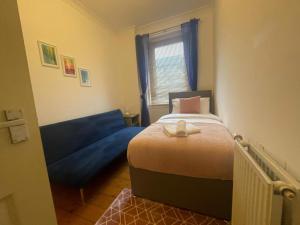 格拉斯哥Irongray House的一间小卧室,配有一张床和一张蓝色的沙发
