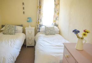 海尔Water's View Cottage, Hayle的一间带两张床的卧室和鲜花花瓶