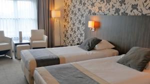 芬莱阿斯特利亚酒店的酒店客房带两张床和一张桌子以及椅子。