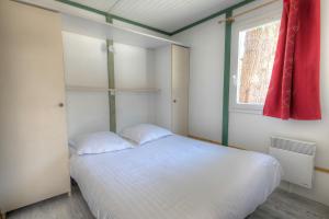 萨尔拉拉卡内达Les Chalets du Périgord的卧室配有白色的床和窗户。
