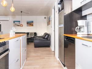 Trans6 person holiday home in Lemvig的一间带白色橱柜的厨房和一间客厅