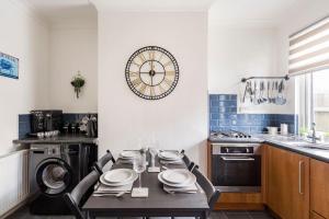 霍伊莱克Charming Terraced House in Central Hoylake的厨房配有桌子和墙上的时钟