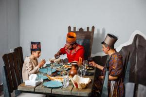 LchashenThe Forgotten Kingdom的三人坐在餐桌旁吃食物