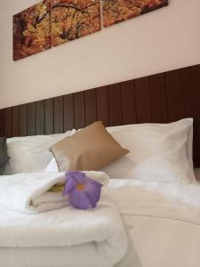 Ban Mo NaeCOWORX Koh Lanta的一张带毛巾的白色床和一朵紫色的花