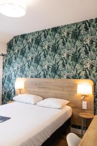 瓦讷Logis Golfe Hotel的一间卧室配有一张带绿色和白色壁纸的床