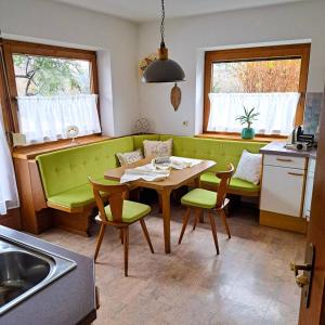 克拉姆萨赫Ferienwohnung Waldblick的厨房配有绿色的沙发、桌子和椅子